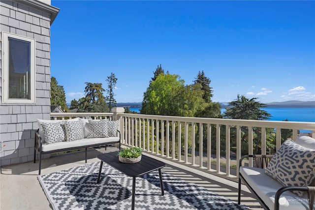 wooden terrace featuring a water view and outdoor lounge area