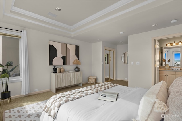 bedroom featuring a raised ceiling, crown molding, ensuite bath, and light colored carpet