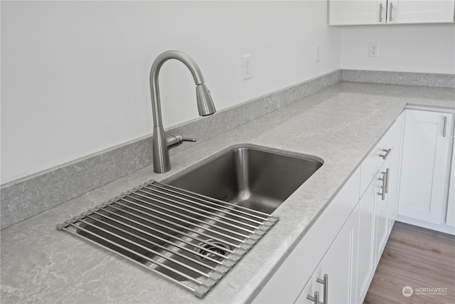 interior details featuring white cabinets, light hardwood / wood-style floors, and sink