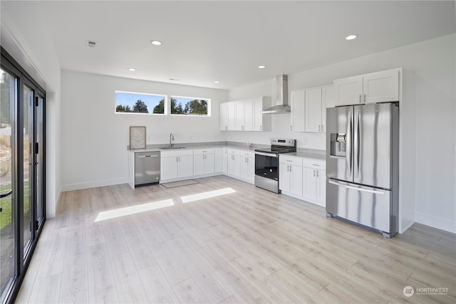 kitchen featuring stainless steel appliances, white cabinetry, wall chimney exhaust hood, and sink