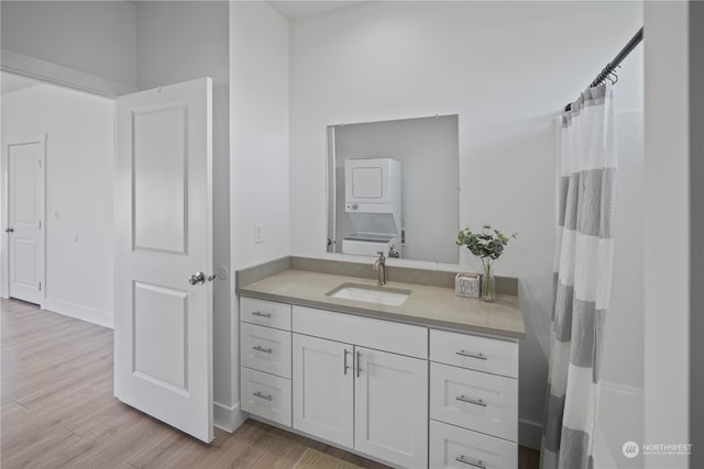 bathroom featuring stacked washer and dryer, vanity, and hardwood / wood-style floors