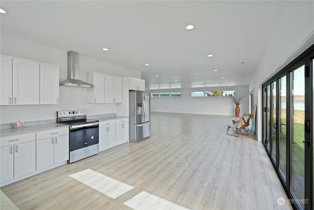 kitchen with white cabinetry, wall chimney exhaust hood, light wood-type flooring, and appliances with stainless steel finishes