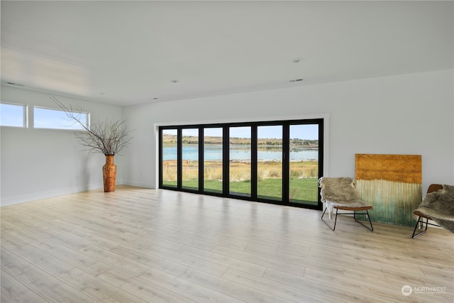 spare room with a water view and light wood-type flooring