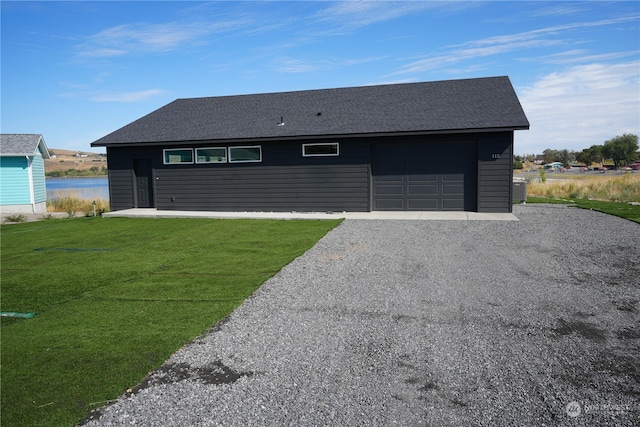 view of front of house with an outbuilding, a water view, a front yard, and a garage