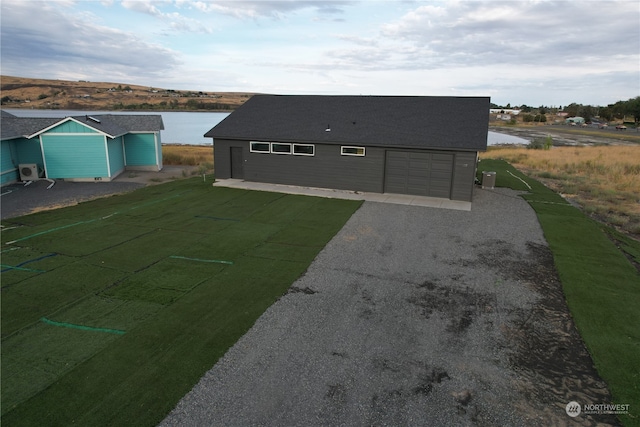 exterior space featuring a lawn, a garage, and a water view