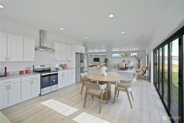 kitchen featuring white cabinets, light hardwood / wood-style floors, wall chimney range hood, and stainless steel appliances