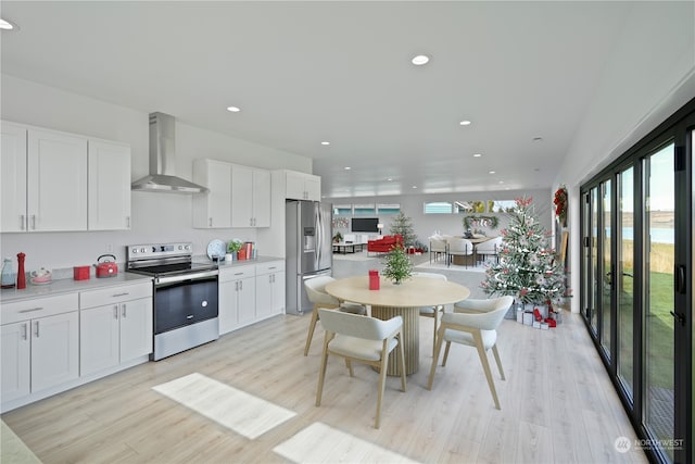 kitchen featuring white cabinets, stainless steel appliances, wall chimney exhaust hood, and light hardwood / wood-style floors