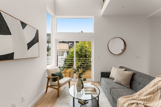 living area featuring baseboards, a high ceiling, and light wood-style flooring