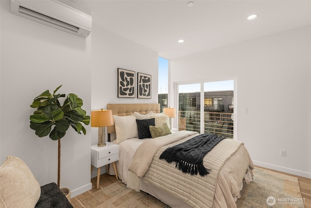 bedroom with a wall mounted air conditioner, baseboards, recessed lighting, and light wood-style floors