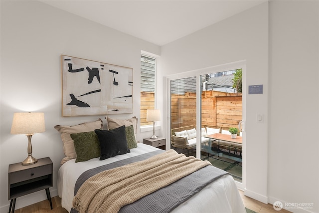bedroom featuring baseboards, light wood-style flooring, and access to outside