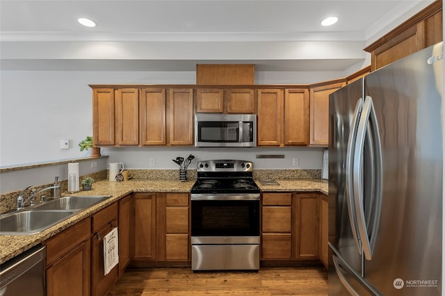 kitchen featuring appliances with stainless steel finishes, light hardwood / wood-style flooring, light stone countertops, and sink