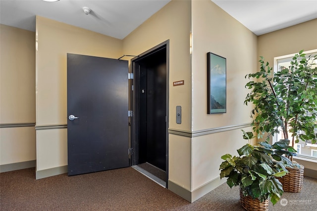 corridor featuring dark carpet and elevator