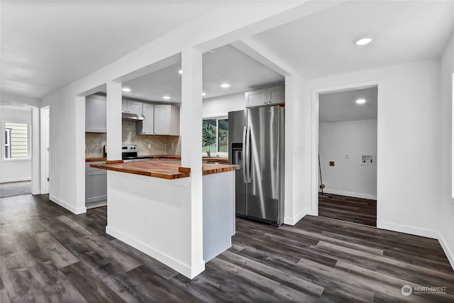 kitchen featuring a wealth of natural light, stainless steel appliances, dark hardwood / wood-style floors, and wood counters