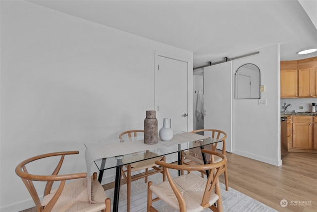 dining room featuring a barn door, light hardwood / wood-style floors, and sink