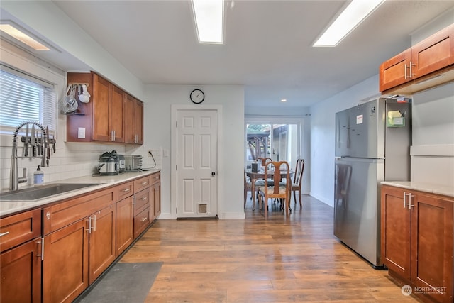 kitchen featuring backsplash, sink, stainless steel fridge, and light wood-type flooring