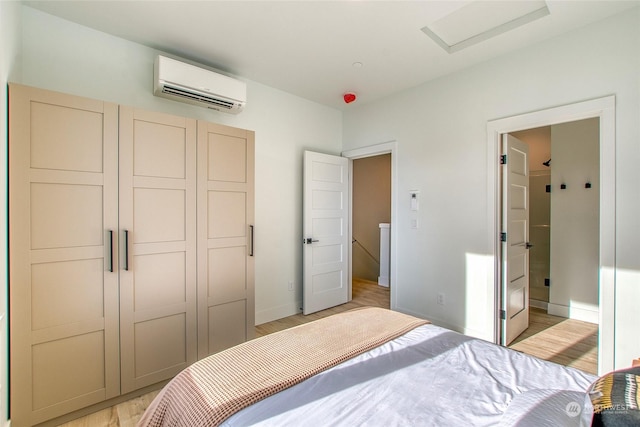 bedroom featuring an AC wall unit, light hardwood / wood-style floors, and a closet