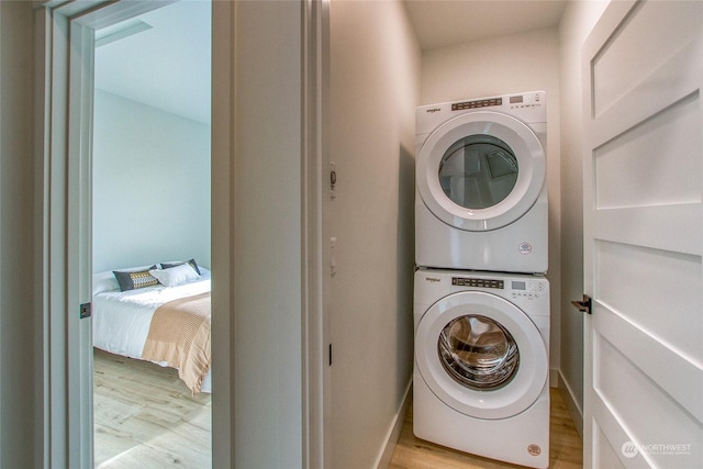 laundry room with light hardwood / wood-style flooring and stacked washer / dryer