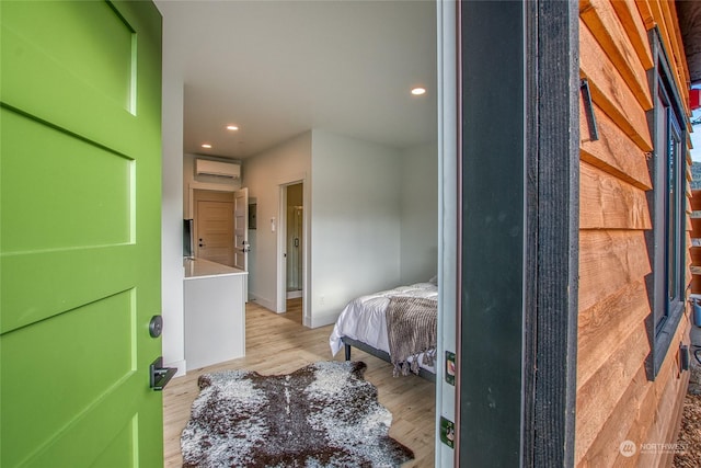 bedroom with a wall mounted AC and light hardwood / wood-style flooring