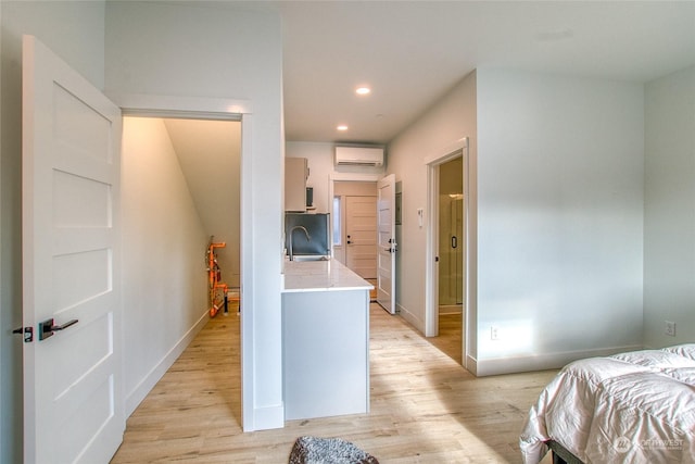 bedroom featuring sink, a wall mounted air conditioner, and light hardwood / wood-style floors