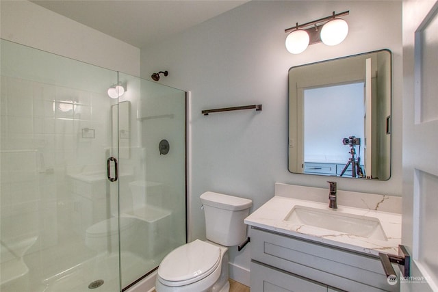 bathroom with a shower with door, vanity, and toilet