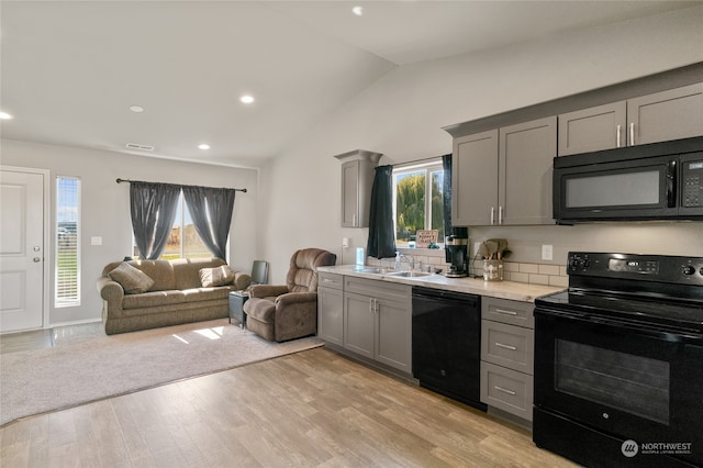 kitchen with black appliances, lofted ceiling, light hardwood / wood-style flooring, and a wealth of natural light