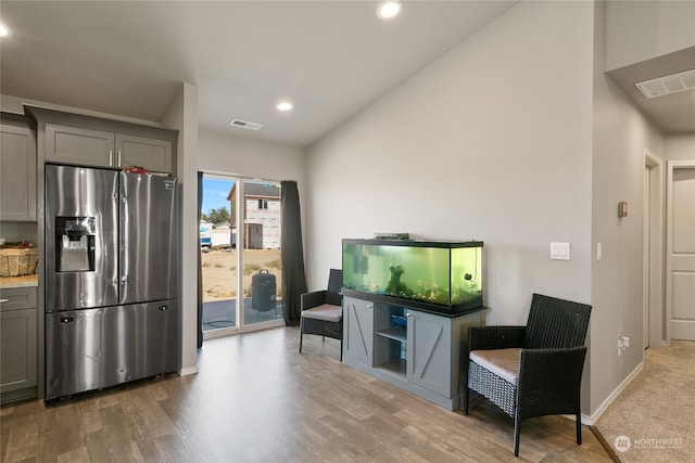 kitchen featuring gray cabinets, light hardwood / wood-style flooring, stainless steel fridge, and lofted ceiling