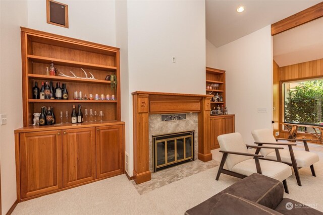 living room featuring indoor bar, vaulted ceiling, light colored carpet, and a fireplace