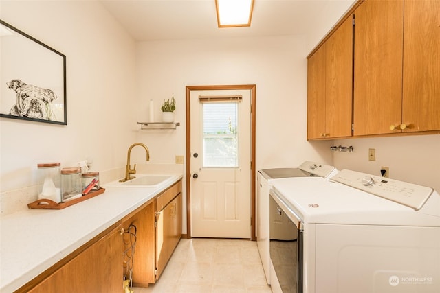 clothes washing area with washer and clothes dryer, cabinet space, and a sink