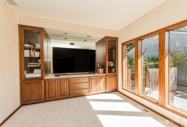 unfurnished living room with baseboards, light colored carpet, and visible vents