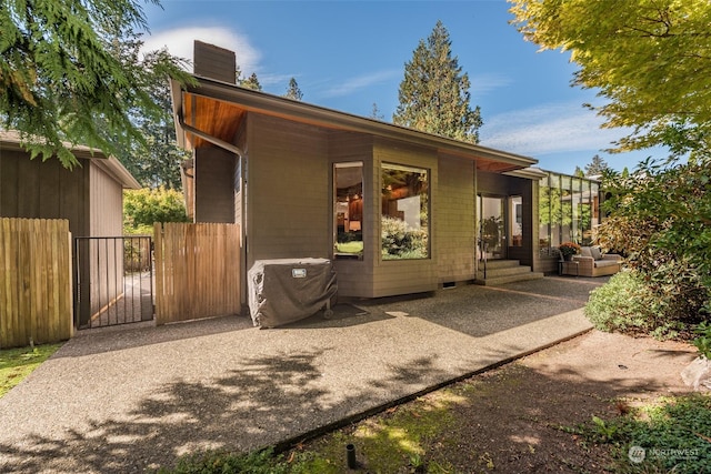 exterior space with a chimney, fence, a gate, and a patio area