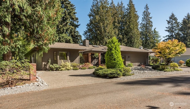 view of front of house with driveway, an attached garage, and a chimney