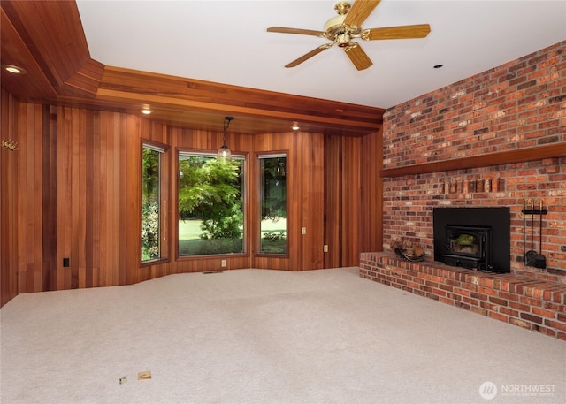 125 Arnold Palmer Pkwy, Sequim, WA 98382 - unfurnished living room featuring carpet flooring, wooden walls, a ceiling fan, and a wood stove