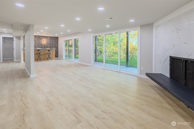 unfurnished living room featuring a wealth of natural light, light hardwood / wood-style floors, and a fireplace