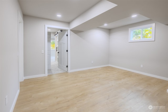 interior space with light wood-type flooring and a barn door