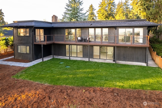 rear view of property featuring a balcony and a yard