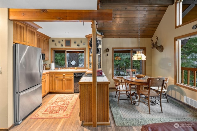 kitchen with freestanding refrigerator, a peninsula, light wood-style floors, tile counters, and dishwasher