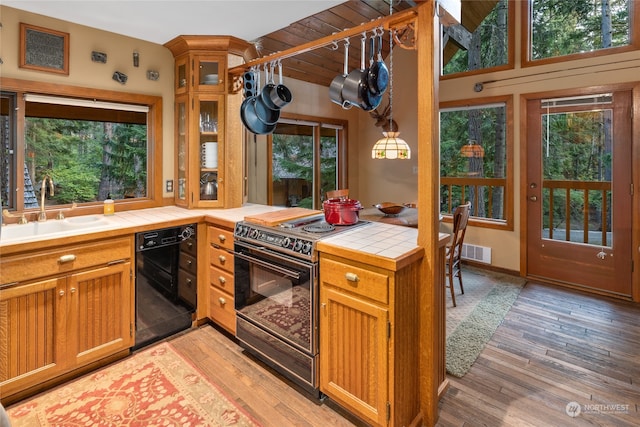 kitchen featuring black appliances, tile counters, wood ceiling, light hardwood / wood-style floors, and sink