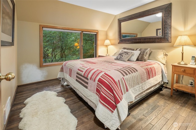 bedroom featuring baseboards, lofted ceiling, wood finished floors, and visible vents