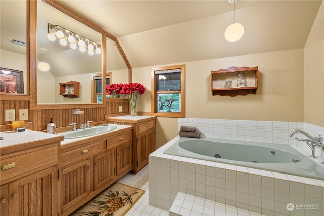 bathroom with lofted ceiling, vanity, tile patterned flooring, and a relaxing tiled tub