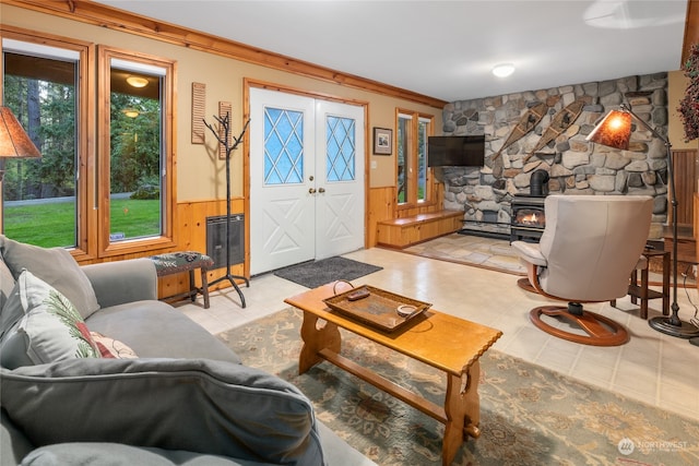 living room featuring ornamental molding, a wood stove, french doors, and wooden walls