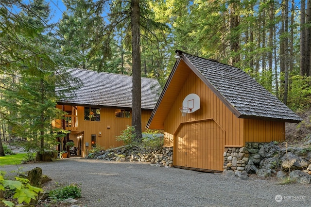 view of side of home featuring an outbuilding, stone siding, and a detached garage
