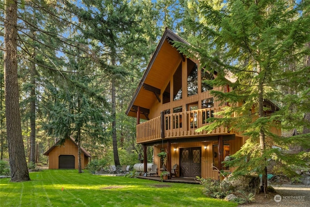back of house featuring a garage, an outbuilding, a wooden deck, and a yard