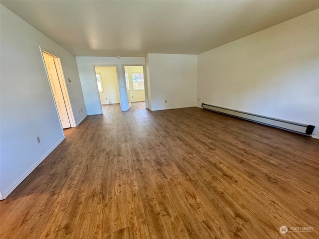 empty room with dark wood-type flooring and a baseboard radiator