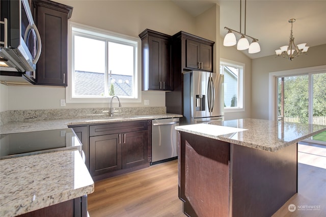 kitchen with light wood-type flooring, sink, a kitchen island, an inviting chandelier, and stainless steel appliances