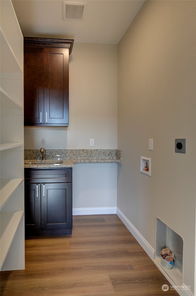 clothes washing area featuring hookup for a washing machine, cabinets, light hardwood / wood-style floors, and electric dryer hookup