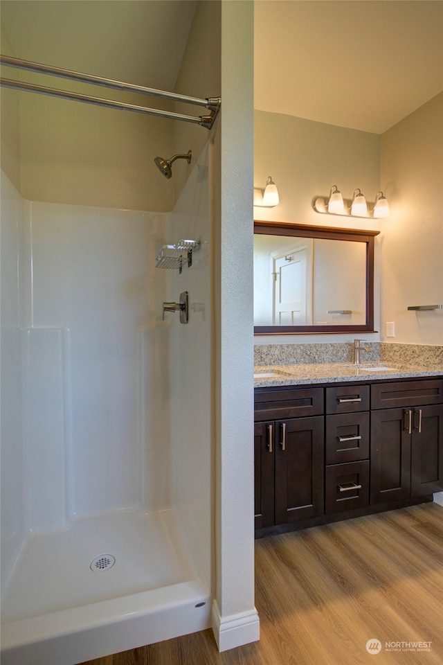 bathroom featuring walk in shower, wood-type flooring, and vanity