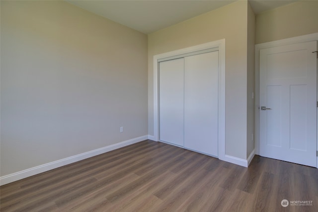 unfurnished bedroom with a closet and dark wood-type flooring