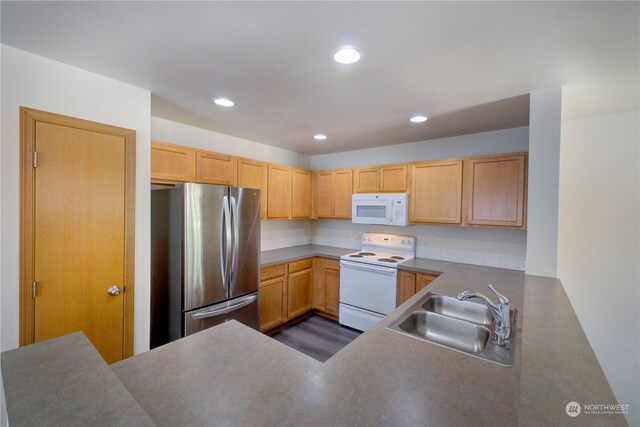 kitchen featuring light brown cabinetry, white appliances, sink, and kitchen peninsula