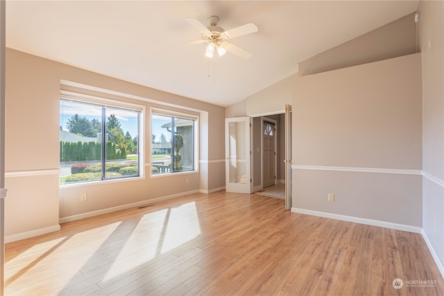 empty room with ceiling fan, vaulted ceiling, and light wood-type flooring