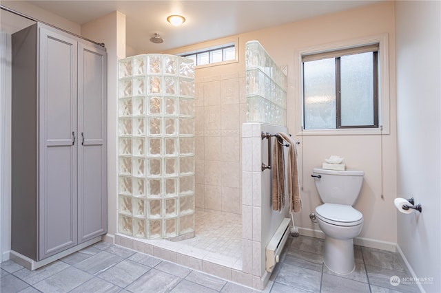 bathroom featuring a tile shower, toilet, and a healthy amount of sunlight